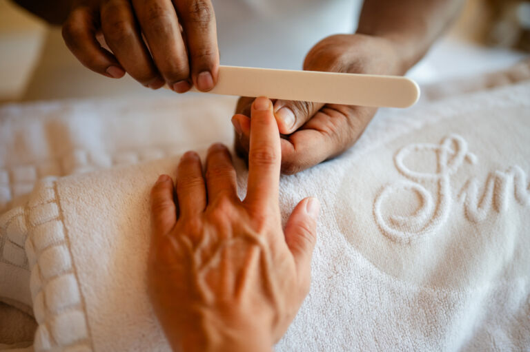 De spa-medewerker voert een manicure uit bij de klant