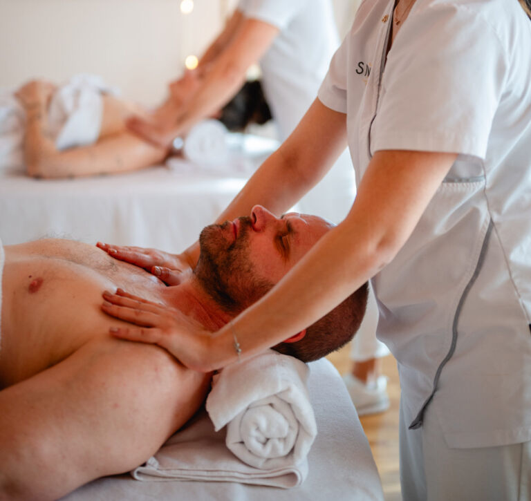 Twee masseurs geven een schoudermassage met een partner