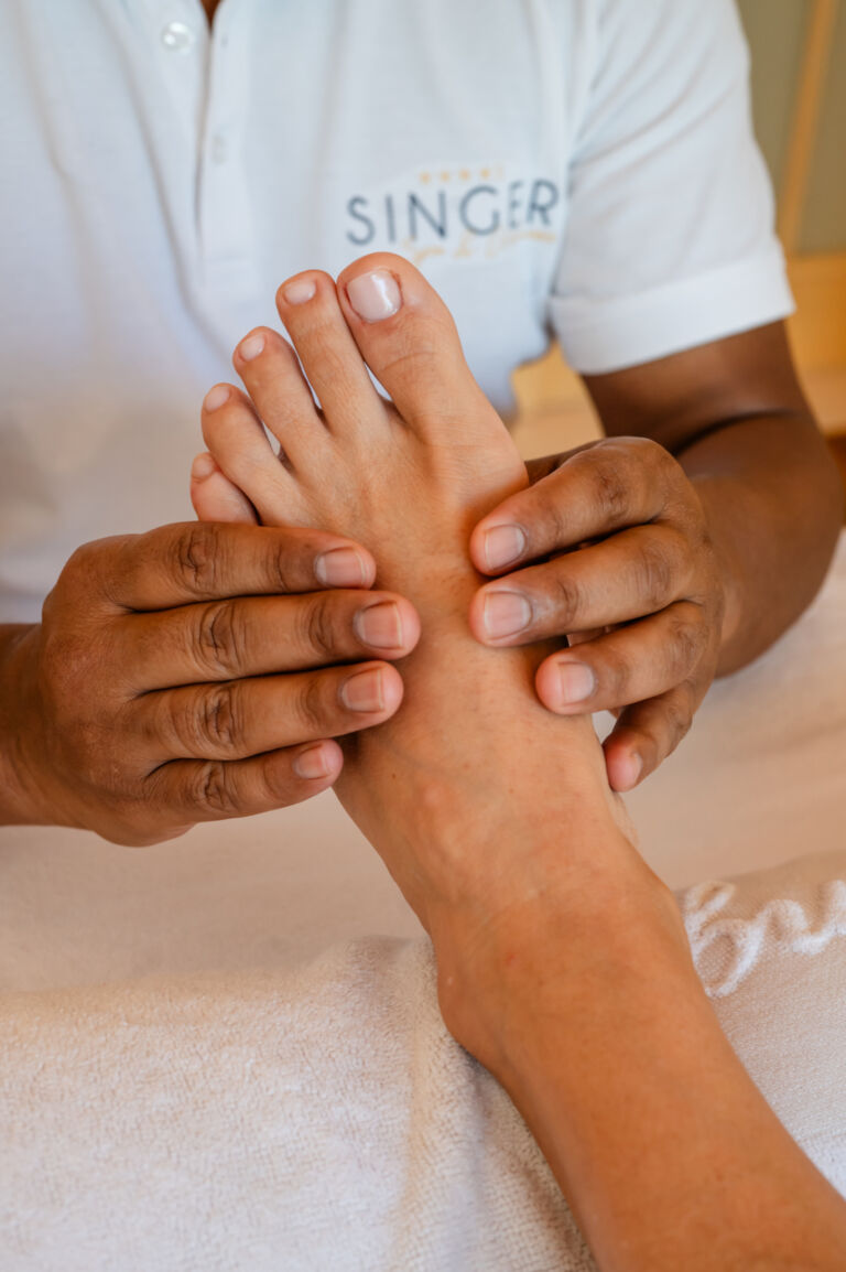 Een medewerker van de spa masseert de voeten van een klant