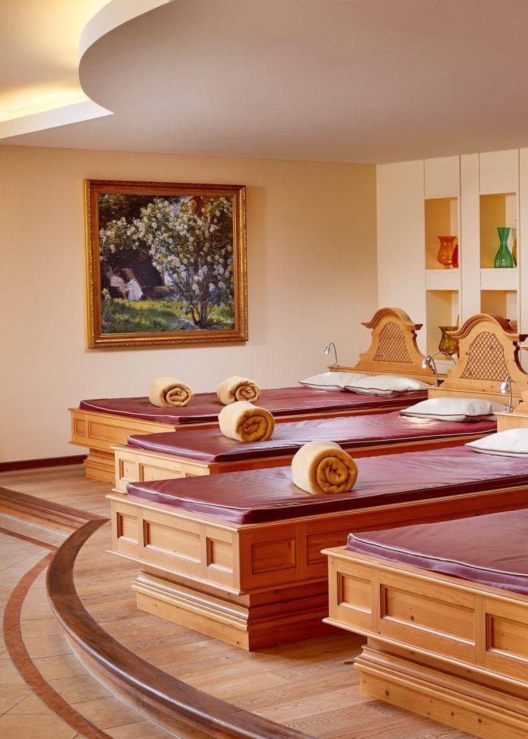Holzliegen reihen sich mit aufgerollten Handtüchern, bereit zum Entspannen in einem warmen, ruhigen Spa-Raum.
